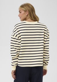 Gestreiftes Langarmshirt in Creme und Marineblau, lässige Passform mit überschnittenen Schultern. Weicher Stoff, Rundhalsausschnitt und gerippte Bündchen.