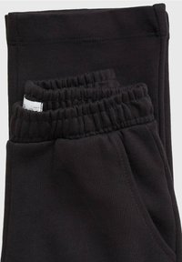 Svarta joggerbyxor i mjukt, texturerat tyg, med elastisk midja och två sidofickor. Enkel och funktionell design.