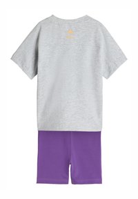 Szary T-shirt z krótkim rękawem z żółtymi logo Adidas i Disney, zestawiony z fioletowymi elastycznymi szortami. Miękka, lekka tkanina, casualowy design.