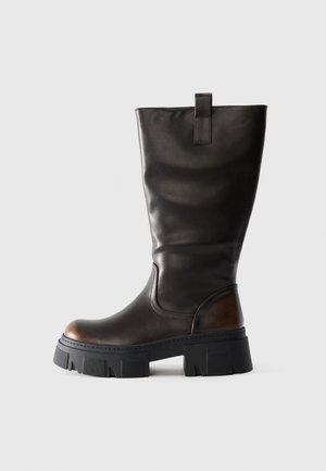 Tall black leather boot with chunky black platform sole and brown accent on heel, side view on light gray background.