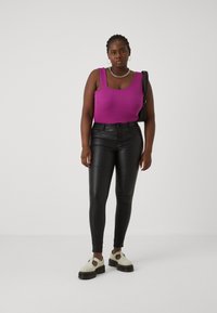 Fitted, ribbed, purple tank top paired with black, high-waisted faux leather skinny jeans and light colored, chunky-soled shoes.