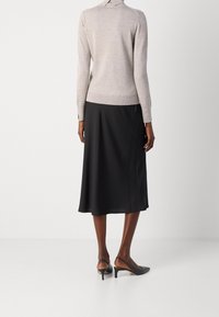 Jasnoszary sweter z kołnierzykiem, zestawiony z czarną spódnicą o długości do połowy łydki. Spódnica ma gładką fakturę, a do tego czarne czółenka na pasku z tyłu.