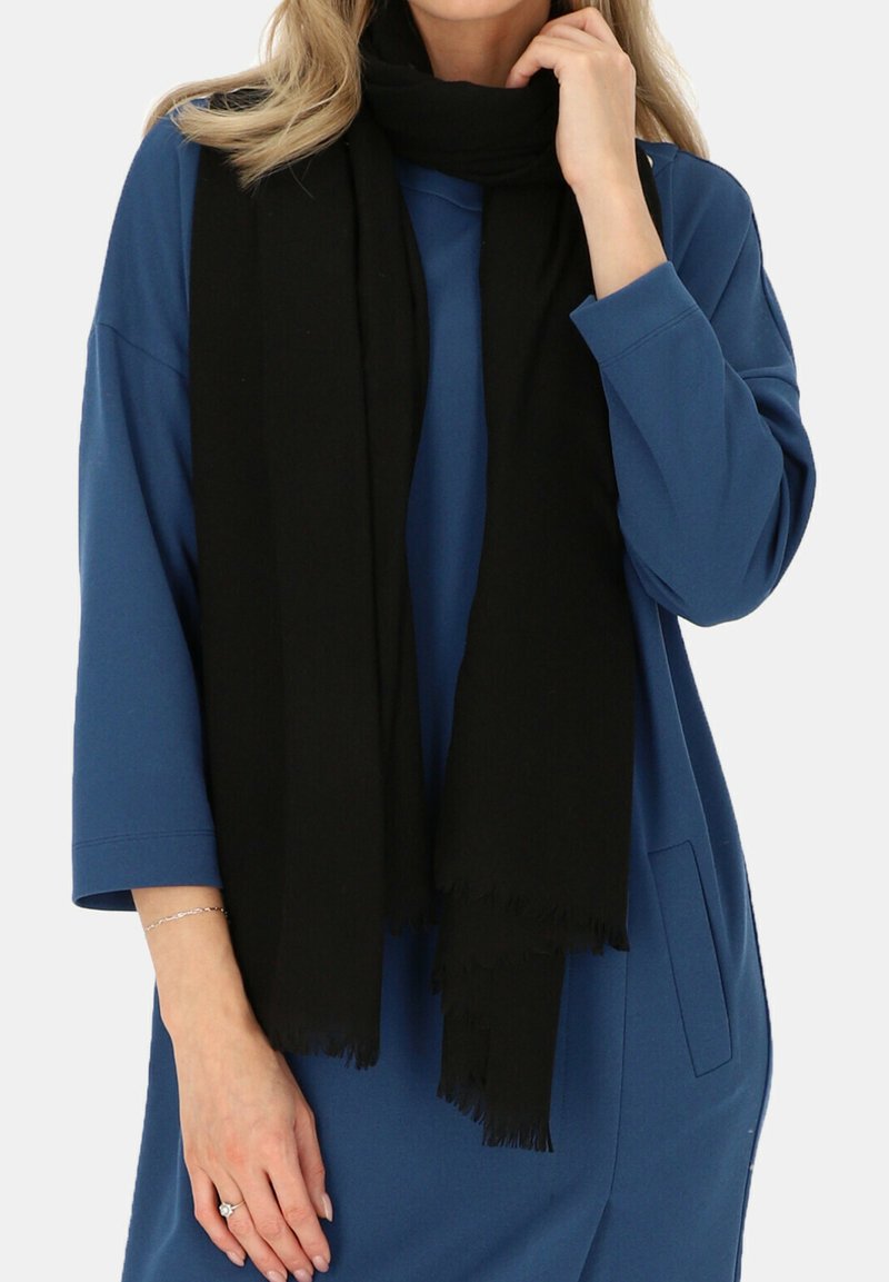 Czarny szalik z miękkiego materiału, układający się wokół szyi, z frędzlami na brzegach. Noszony na niebieskiej, luźnej koszuli.