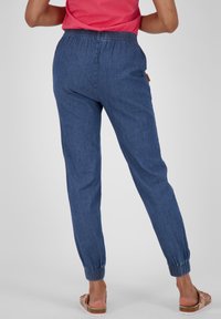 Modré chambray kalhoty na jogu se stahovacími šňůrkami v pase, elastickými manžetami a bočními kapsami, doplněné o růžový top a sandály.