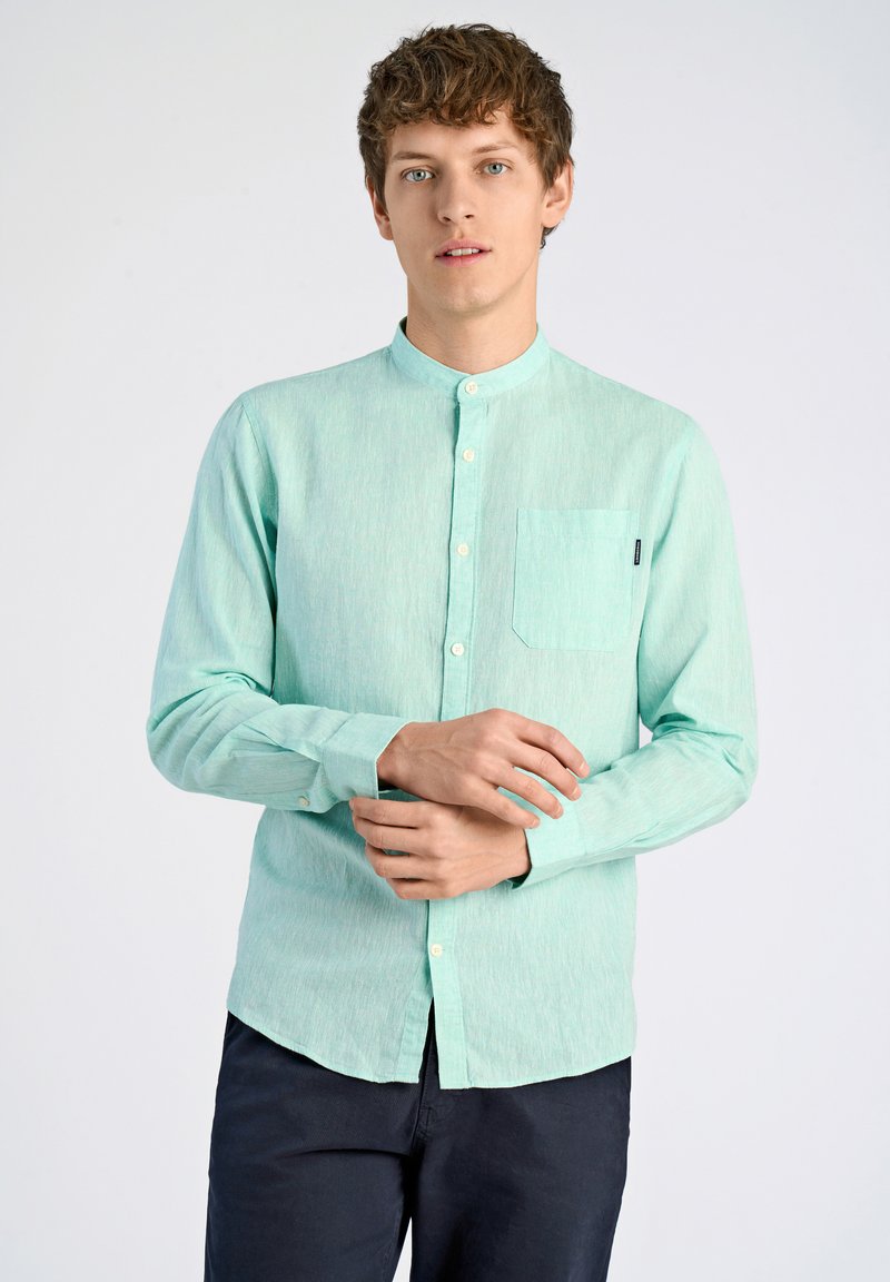 Vaalean mintunvihreä pitkähihaisuus paita, jossa on mandariinikaulus, etutasku ja nappisuljenta. Kankaassa on hienovarainen rakenne ja kiilto.