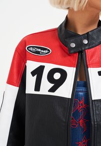 Leather jacket featuring bold red, white, and black panels; design includes stitched number "19" and Ed Hardy logo; sturdy snaps at collar.