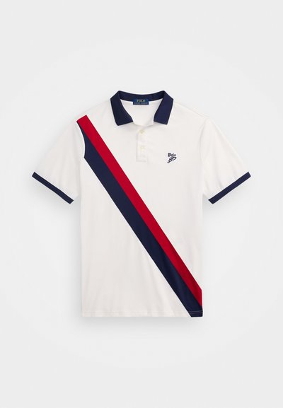 Camisa polo branca com colarinho e punhos azuis marinho. Apresenta uma faixa diagonal vermelha e azul marinho. Logótipo bordado no peito.