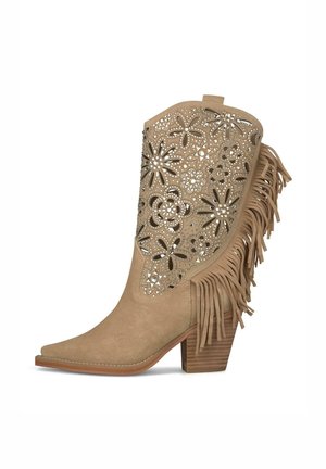 Bota vaquera de ante beige con recortes florales, tachuelas plateadas, flecos laterales y tacón apilado de madera.