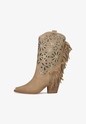 Stivale da cowboy in suede beige con ritagli floreali, borchie d'argento, frange laterali e tacco impilato in legno.