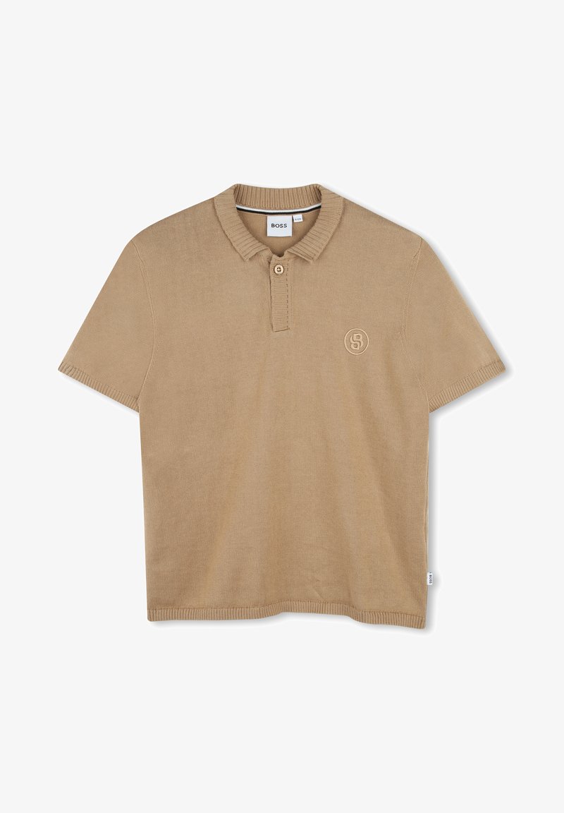 Polo beige en coton côtelé, avec un col à trois boutons et un petit logo sur la poitrine gauche. Manches courtes, coupe décontractée.