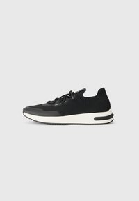 Pantofii sport negri au un superior din material tricotat, cu vârf rotunjit și o talpă albă contrastantă, dotată cu un grip texturat. Șireturile sunt integrate în design.