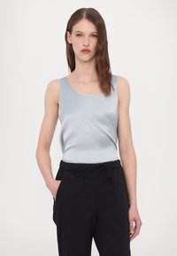 Light blue satin tank top with a round neckline, sleeveless design, paired with black pants featuring a drawstring waist and side pockets.