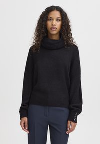 Pull noir à col roulé, avec une coupe décontractée, en tissu tricoté texturé, avec des accents de boutons sur les manches et un ourlet côtelé.