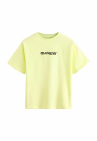Gul bomulds t-shirt med korte ærmer, rund halsudskæring og sort trykt tekst "SOLAR MOTION NEW WAVE" på forsiden. Glat tekstur.