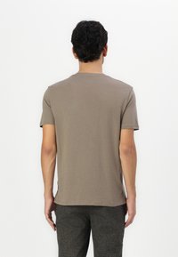 Brown, short-sleeved T-shirt made of smooth fabric, featuring a rounded neckline and a clean design, displayed from the back.