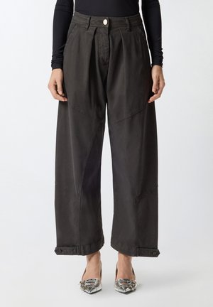 Pantaloni a gamba larga e vita alta in tessuto grigio scuro con pieghe frontali, tasche laterali inclinate e polsini con bottone.