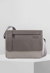 Borsa a spalla in pelle grigia con chiusura a patta, tasca frontale con zip, tracolla regolabile e sezione inferiore di un grigio chiaro contrastante.