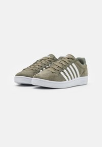 Grønne semskede sneakers med hvide striber og snørebånd, med en rund tå og en flad gummisål. Casual design med tekstureret materiale.