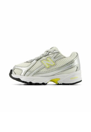 Weißer und silberner New Balance Laufschuh mit gelben Akzenten und Mesh-Gewebe, von der Außenseite auf weißem Hintergrund dargestellt.