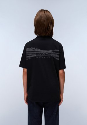 Camiseta negra de manga corta, con un diseño de olas en gris y el texto "NAPAPIJRI" en la parte posterior, hecha de una tela suave con un corte holgado.