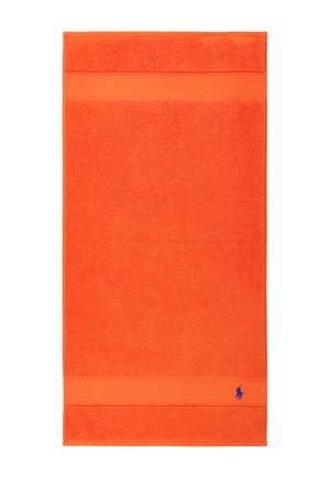 Serviette rectangulaire orange vif avec des bandes texturées près du haut et du bas, ornée d'un petit logo brodé bleu dans le coin inférieur.