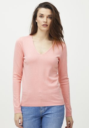 Pull confortable rose clair à col en V avec des manches longues, au design ajusté, texture douce et poignets côtelés, associé à un jean en denim bleu.
