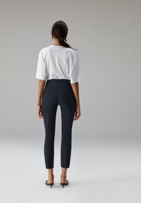 Wit oversized T-shirt met korte mouwen, gecombineerd met nauwsluitende zwarte broek met een gladde textuur en enkellange snit.