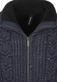 Marineblauwe gebreide trui met een centrale metalen ritssluiting en een zwarte fleece-gevoerde kraag.