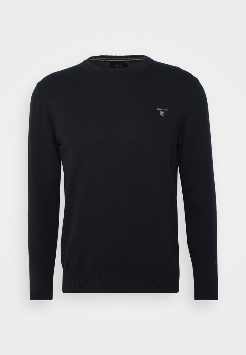 Pull noir à manches longues avec col rond, petit logo GANT et emblème de bouclier sur le côté gauche de la poitrine, poignets et ourlet côtelés.
