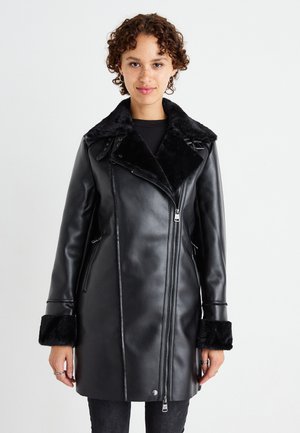 Cappotto in ecopelle nera con un morbido colletto e polsini in pelliccia nera, dotato di chiusura a zip e tasche laterali. Design elegante e su misura.