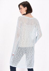 Cardigan in rete azzurro chiaro con maniche lunghe e motivo di lavorazione a maglia aperta, caratterizzato da una vestibilità ampia e fessure laterali per una maggiore libertà di movimento.