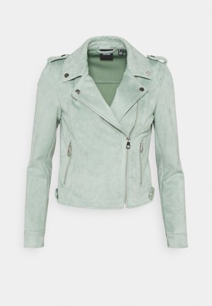 Veste biker en daim vert clair avec fermeture éclair asymétrique à l’avant, deux poches latérales zippées et détails de boutons-pression sur le col et les poignets.