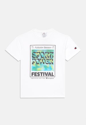 T-shirt en coton blanc avec un imprimé graphique coloré portant le texte "SPORT POWER FESTIVAL" et "sponsorisé par Champion" à l'avant.