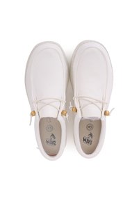 White canvas shoes with a rounded shape, elastic laces, wooden beads, and rubber soles. Features a subtle logo printed inside.