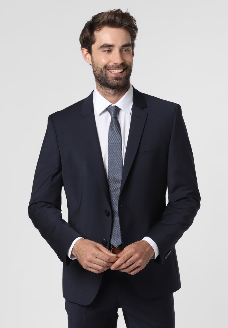 Navy suit with a notched lapel, single-button closure, white dress shirt, and light blue textured tie. Smooth fabric, tailored fit.