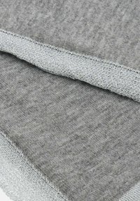 Tessuto grigio lavorato a maglia con un bordo piegato che mostra un motivo a maglia dettagliato e strutturato lungo la cucitura.