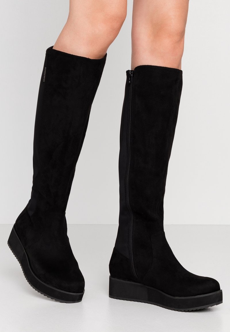 Zwarte laarzen tot de knie van suede, met een stevige platformzool en een zijrits voor gemakkelijke toegang. Glad textuur en een aansluitend ontwerp.