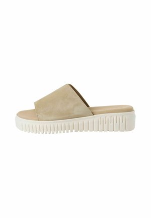 Beige suède slipper sandalen met een brede bovenste band en een witte zool met textuur en groeven. Platte ontwerp voor gemakkelijke draagbaarheid en comfort.