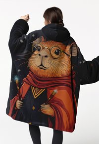 Person som bär en svart kapuschongmantel med en detaljerad illustration av en guinea pig-trollkarl som håller glödande stavar, bär glasögon och en röd scarf.