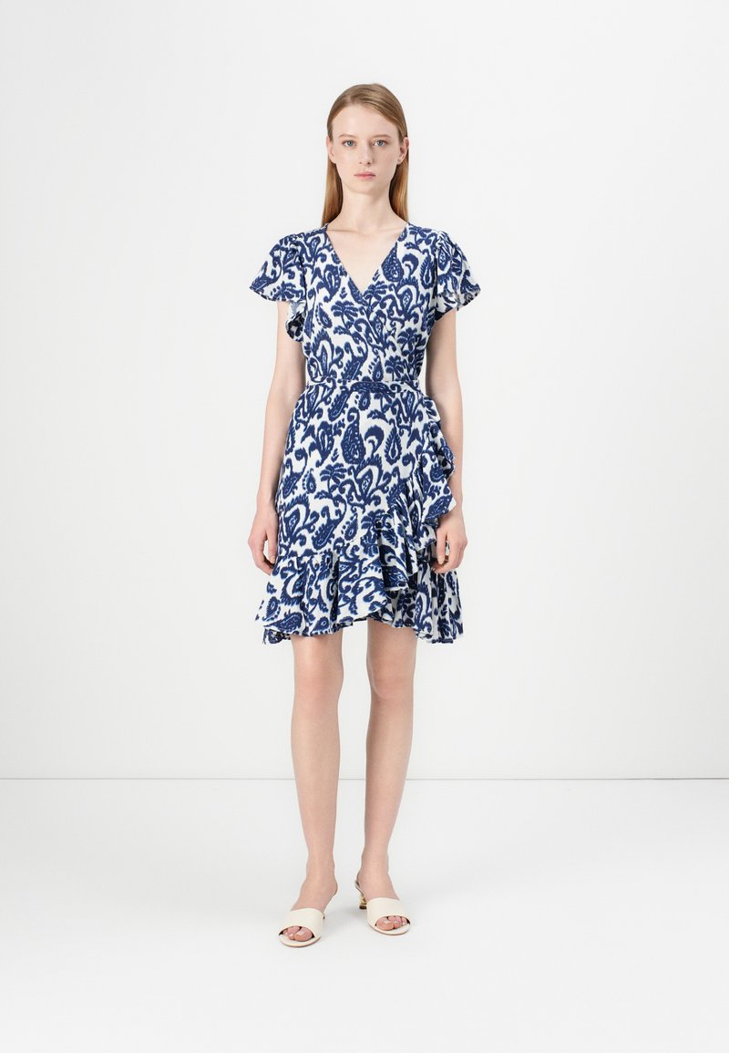 Modrá a biela vzorovaná šaty s výstrihom do V, krátkymi volánovými rukávmi, sťahovaným pásom a rozšíreným lemom s volánmi. Nosí sa s ľahkými topánkami.