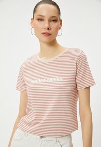 Stribet t-shirt i lys pink og creme, med "limited edition" tekst i hvid. Blødt bomuldsmateriale og standard korte ærmer.