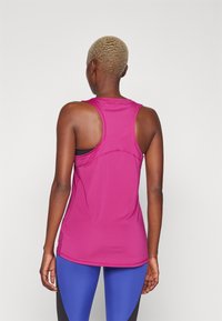 Åtsittande linne i klar rosa, med racerback-design. Tillverkat av ett mjukt, elastiskt tyg med platta sömmar för komfort.