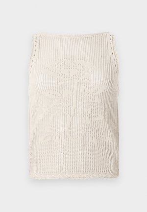 Beige värviline kudum, millel on avatud kudumimuster. Omab lainelisi servi, lillemustrit, mis on kootud kangasse, ja varrukateta lõiget.