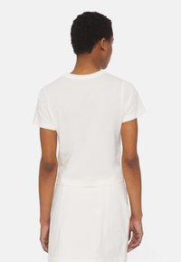 Kurzärmliges, weißes Baumwoll-T-Shirt mit rundem Ausschnitt und cropped Fit, das eine glatte Textur und ein einfaches, klares Design aufweist.