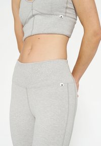 Grijze atletische crop top en high-waisted leggings gemaakt van textuur- en rekbare stof met subtiele naden en een klein logo label op de tailleband.