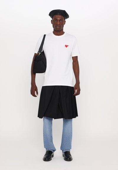 Hvit bomull t-skjorte med rødt hjertegrafikk, svart plisserte skjørt, lyseblå rette jeans, svarte lær-sko og en svart basque.