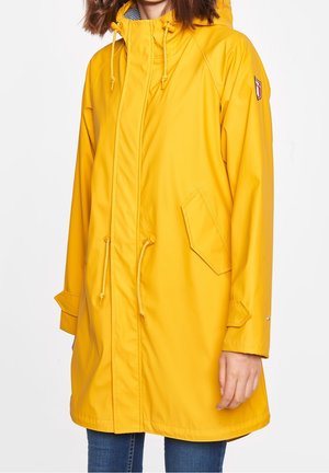 Impermeable amarillo con capucha, cordones y bolsillos laterales. Presenta una textura suave y un diseño corto y holgado.