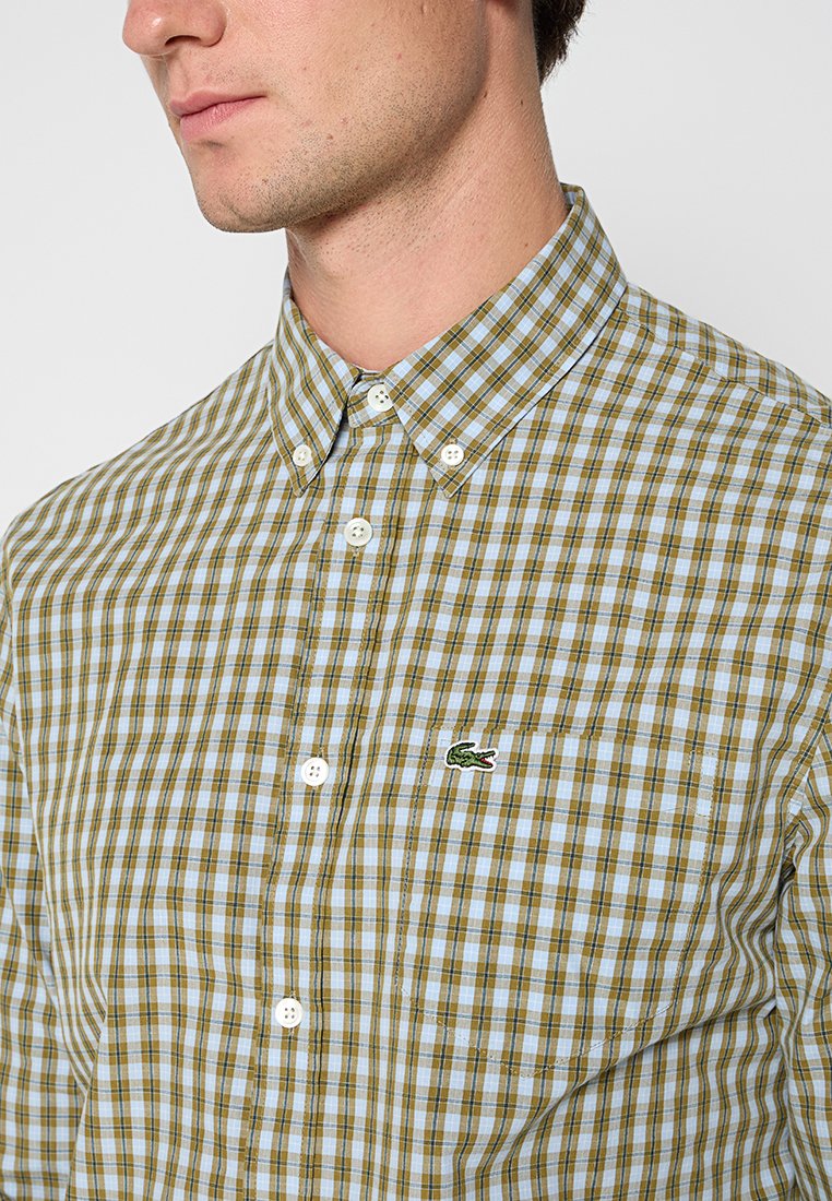Grün und blau karierter Hemd mit Kragen, ausgestattet mit weißen Knöpfen und einem kleinen gestickten Logo auf der Brusttasche.