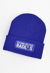 Blue knitted beanie with a turned-up cuff featuring a white patch. Text reads "ICH BIN SELTEN RADLOS" accompanied by a bicycle icon.
