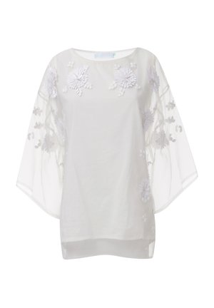 Blusa blanca transparente con mangas anchas, que presenta un intrincado bordado floral blanco y una tela suave y texturizada, creando una apariencia ligera y etérea.